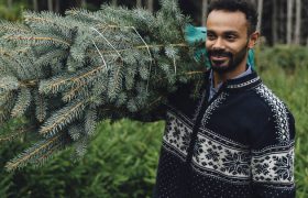 man holding a christmas tree on his shoulder